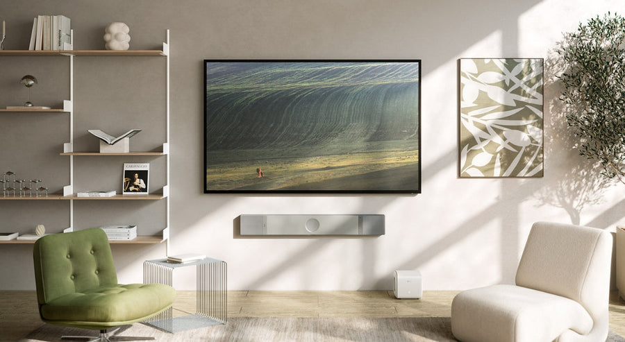 Modern living room with wall-mounted TV and sleek KEF soundbar, illustrating premium home cinema setup in natural light.