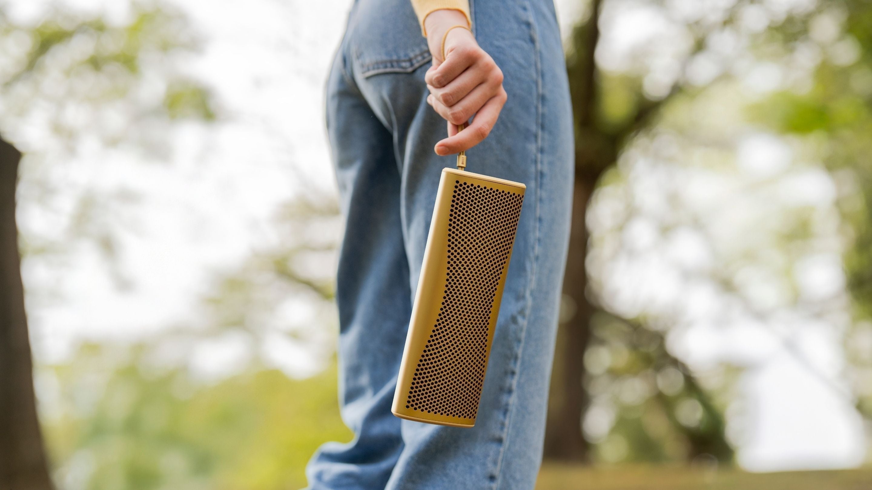 Female holding KEF Muo Portable bluetooth speajer