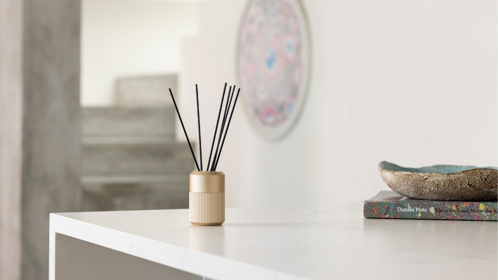 KEF reed diffuser on shelf next to books.